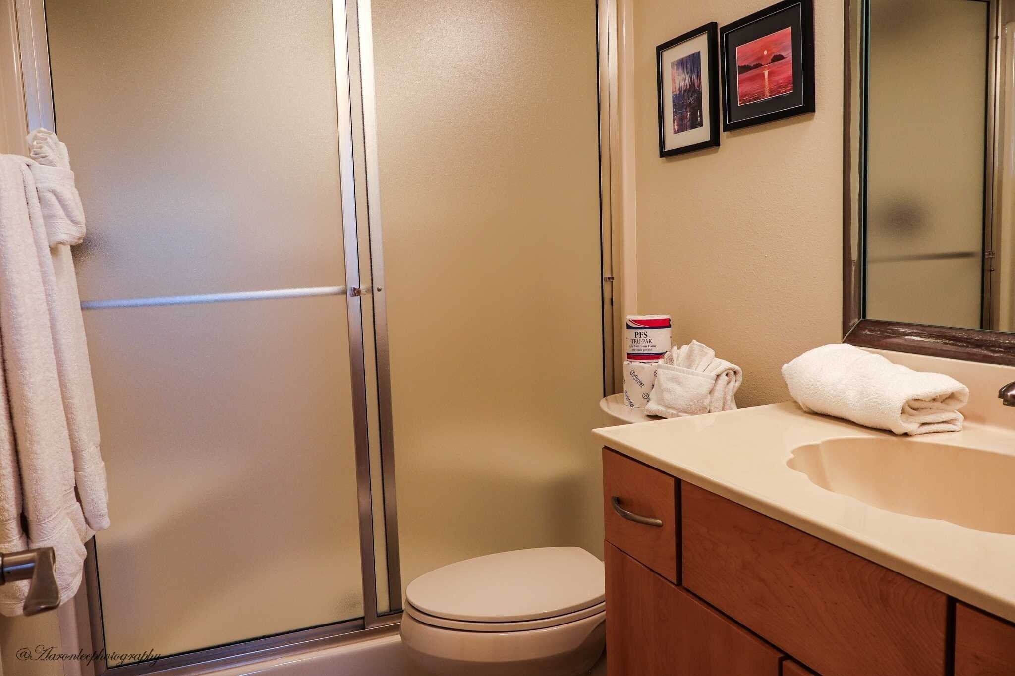 Een badkamer met toilet, wastafel, spiegel en douche.