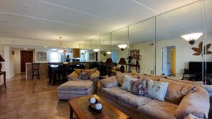 A spacious living room with a large sofa, a coffee table, and a dining area with chairs and a table. - Beachview 208 Minium 2 Bedroom Condo by RedAwning (South Padre Island)