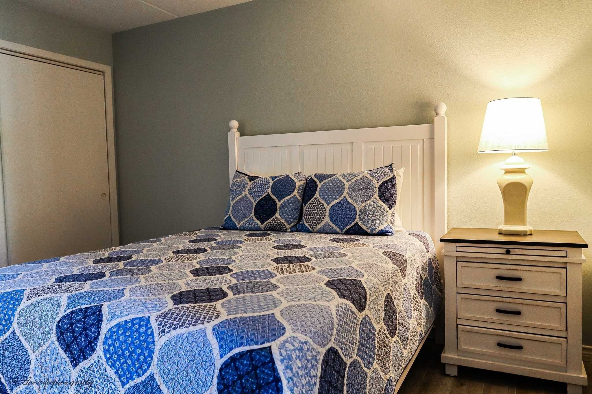 A bedroom with a bed, a nightstand, and a lamp.