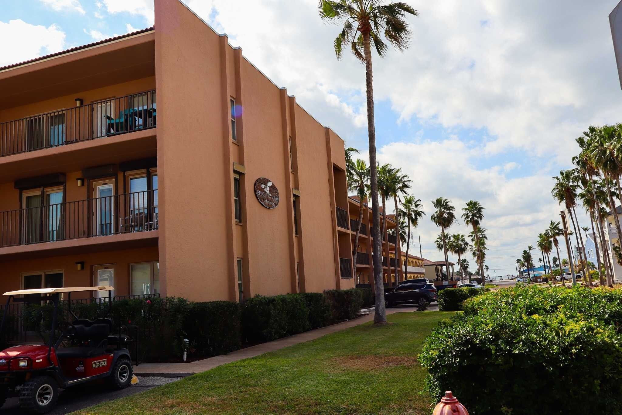 A multi-story hotel with balconies, palm trees, and a golf cart.