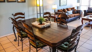 Un coin repas comprenant une table en bois, des chaises, un lampadaire et un canapé avec des coussins.