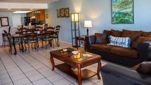 Un salon avec un canapé marron, une table basse en bois et un coin repas comprenant des chaises et une table.