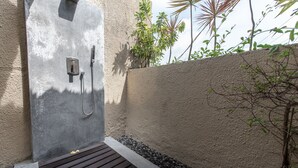 A concrete shower enclosure with a wooden bench and a small plant beside it.