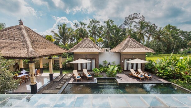 A pool area with lounge chairs and thatched-roof structures.
