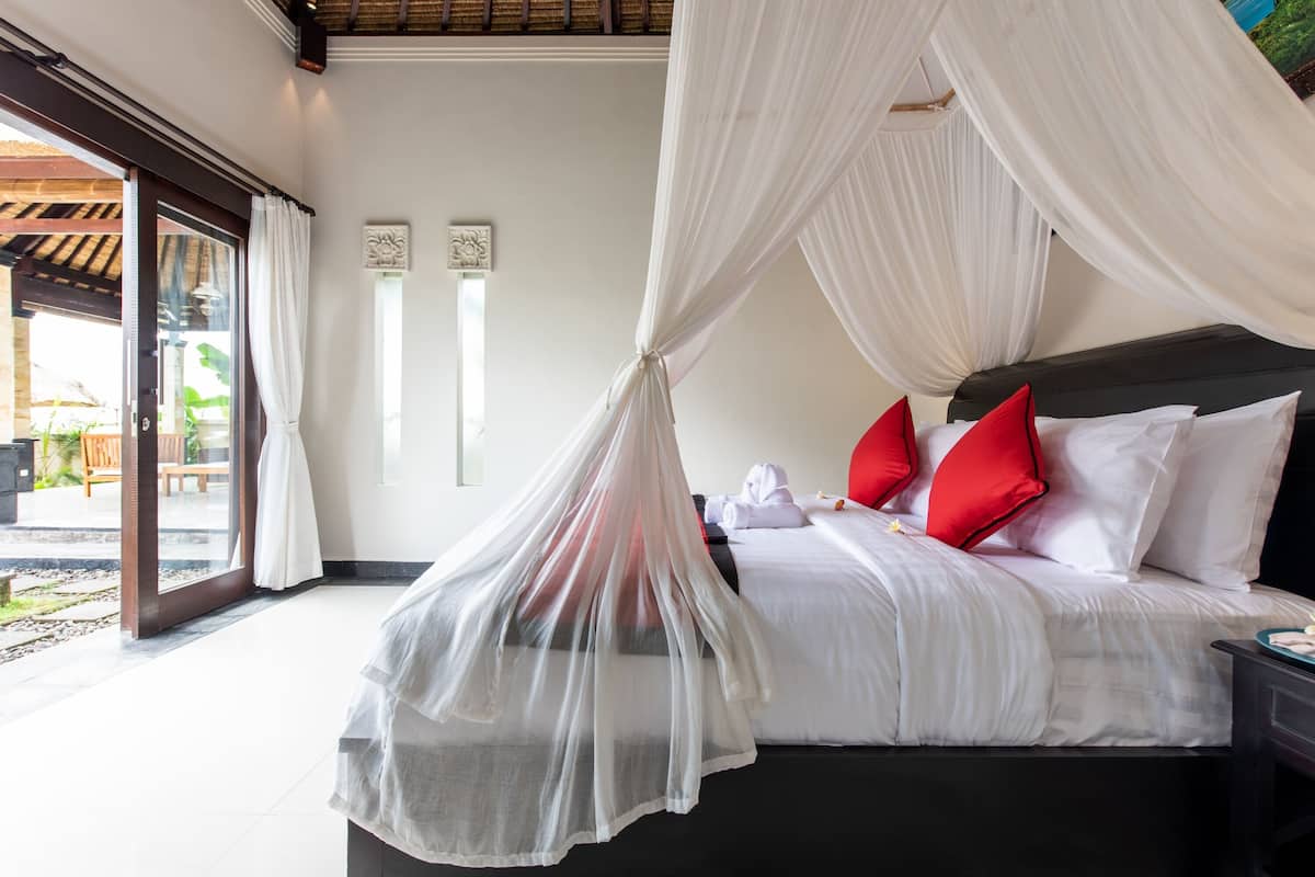 Un dormitorio con cama con dosel, vista al área exterior y puerta que da al exterior.