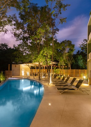 A swimming pool with lounge chairs and a covered seating area.