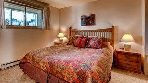 A bedroom with a large bed, two bedside tables with lamps, a window with curtains, and a framed picture on the wall. - Unique, Mountain 4 Br  4 Bedroom Condo - No Cleaning Fee! by RedAwning (Crested Butte)