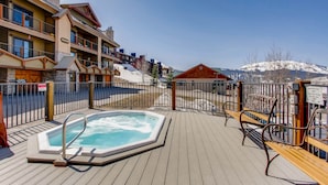 A wooden deck with a hot tub, a fenced area, and a mountain view. - Unique, Mountain 4 Br  4 Bedroom Condo - No Cleaning Fee! by RedAwning (Crested Butte)