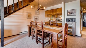 A dining area with a wooden table and chairs, a chandelier, and a staircase. - Unique, Mountain 4 Br  4 Bedroom Condo - No Cleaning Fee! by RedAwning (Crested Butte)