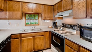 A kitchen with wooden cabinets, a stainless steel sink, a stove, and a microwave. - Unique, Mountain 4 Br  4 Bedroom Condo - No Cleaning Fee! by RedAwning (Crested Butte)