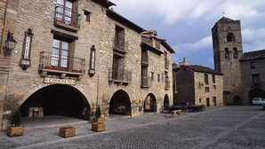 Un edificio histórico de piedra con letrero de hotel, una torre de campanas y calles empedradas.