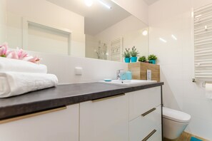 Une salle de bain moderne avec un lavabo blanc, un miroir et une serviette posés sur le comptoir.