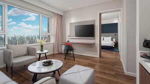 A modern hotel room with a city view, a flat-screen TV, a bed, and a small seating area with a table and chairs. - Holiday Inn Express Yinchuan Downtown by IHG (Yinchuan)