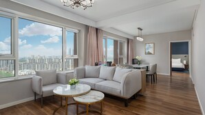 Un salon moderne avec un canap é d’angle, une table à manger et une vue sur le paysage urbain grâce à de grandes fenêtres.