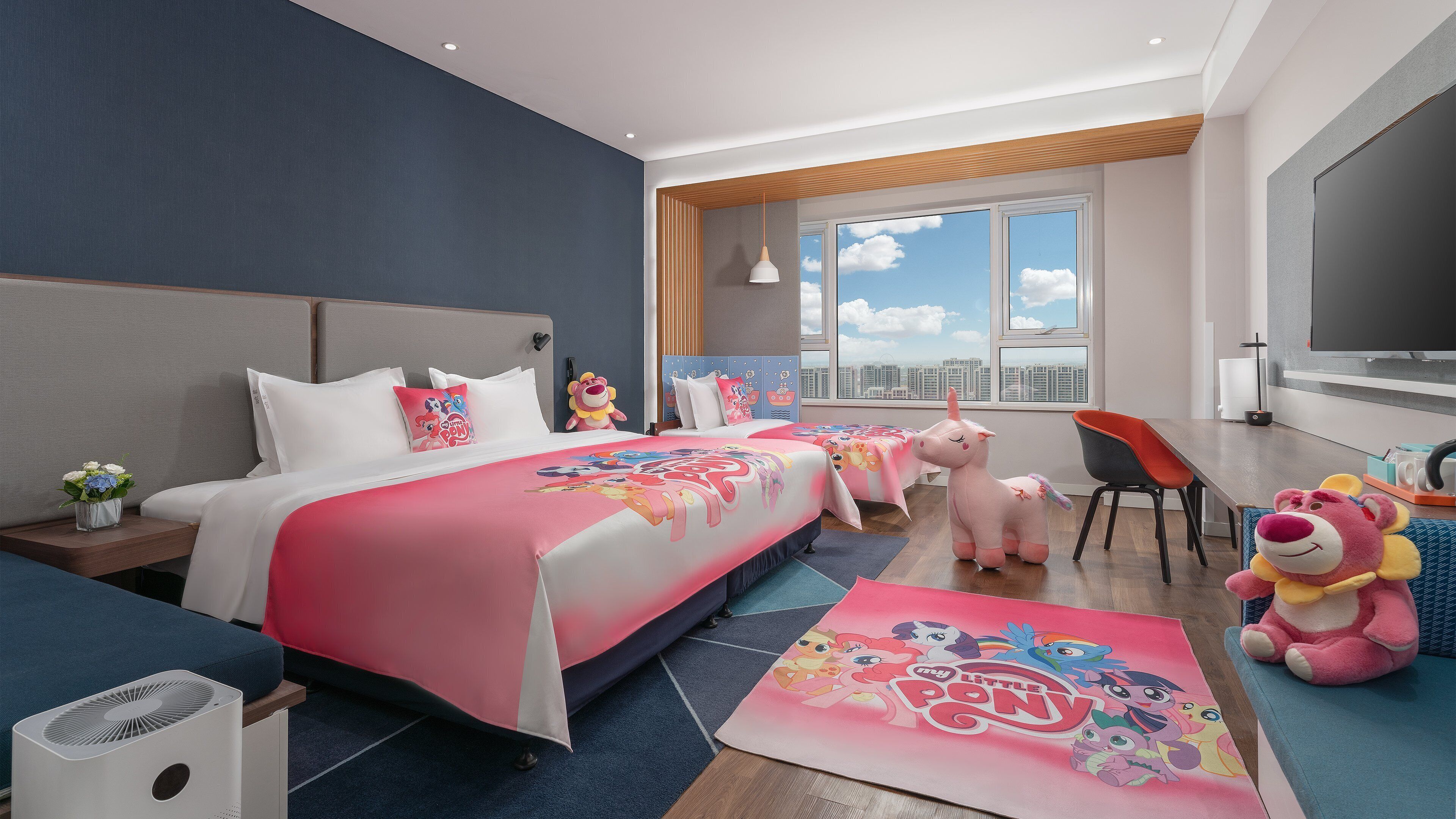 A hotel room with a large bed, a desk, a chair, a TV, and a window with a city view.