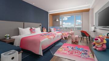 A hotel room with a large bed, a desk, a chair, a TV, and a window with a city view.