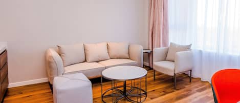Una sala de estar moderna con sofá, reposapiés y una mesa de centro redonda.