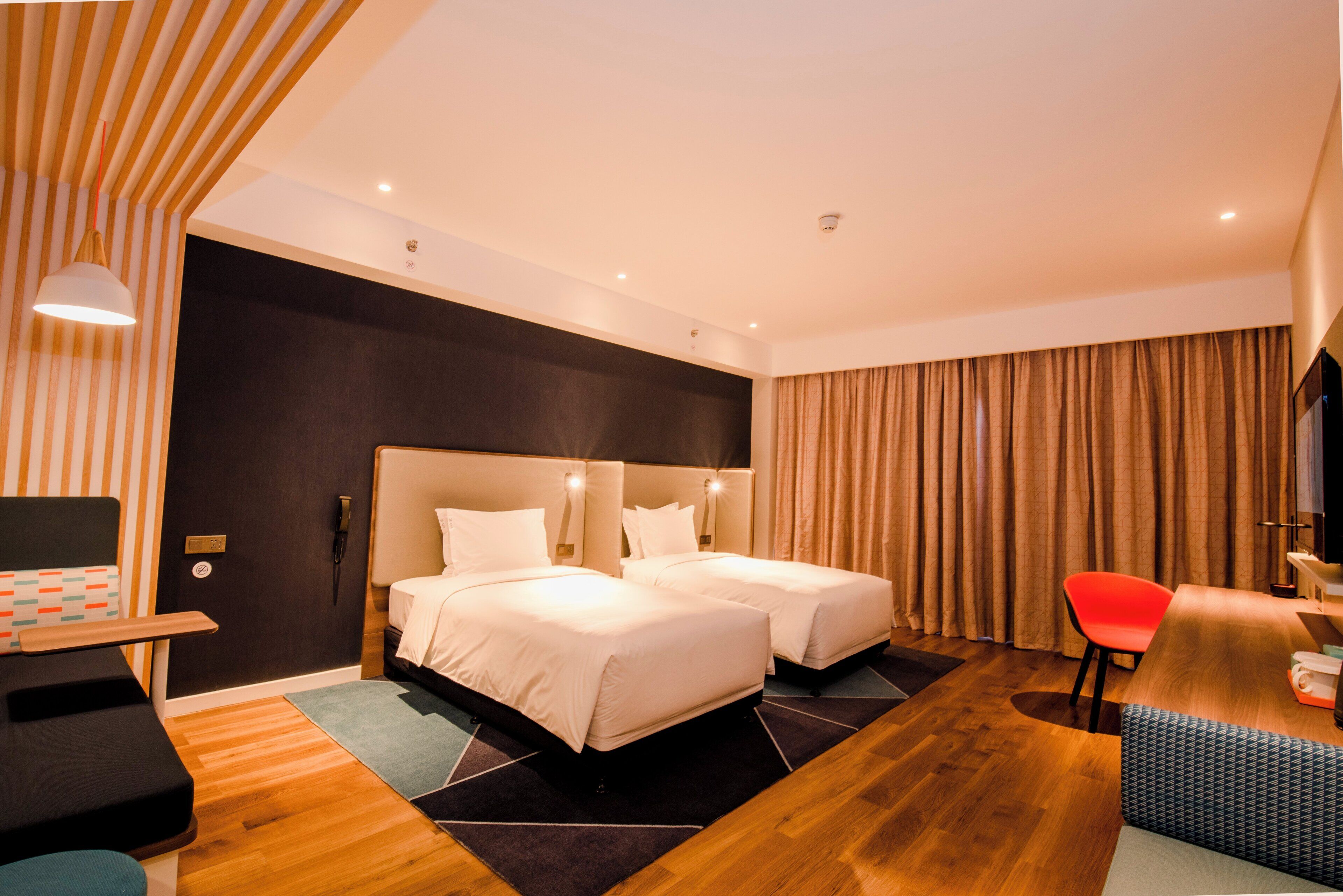 Une chambre d’hôtel avec un grand lit, deux tables de chevet, un bureau, une chaise et un téléviseur.