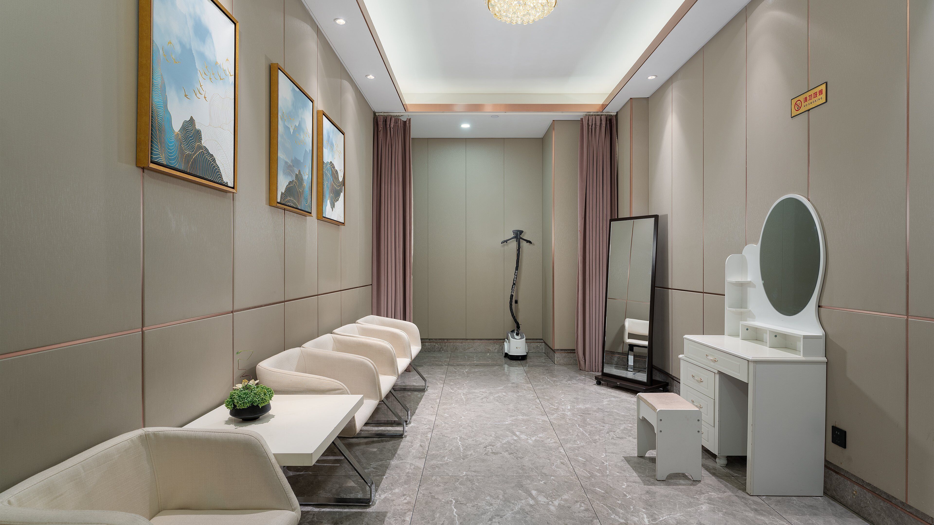 A hotel room with a long bench seating area, a vanity with a mirror, and a standing vacuum cleaner.