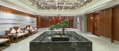 A lobby with a central water feature, seating area, and wooden paneling.