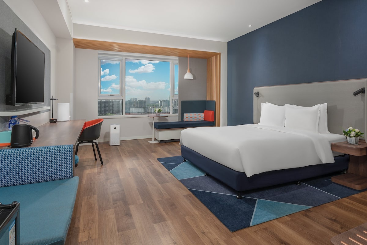 Una habitación de hotel moderna con una cama grande, un escritorio, una silla y un televisor.