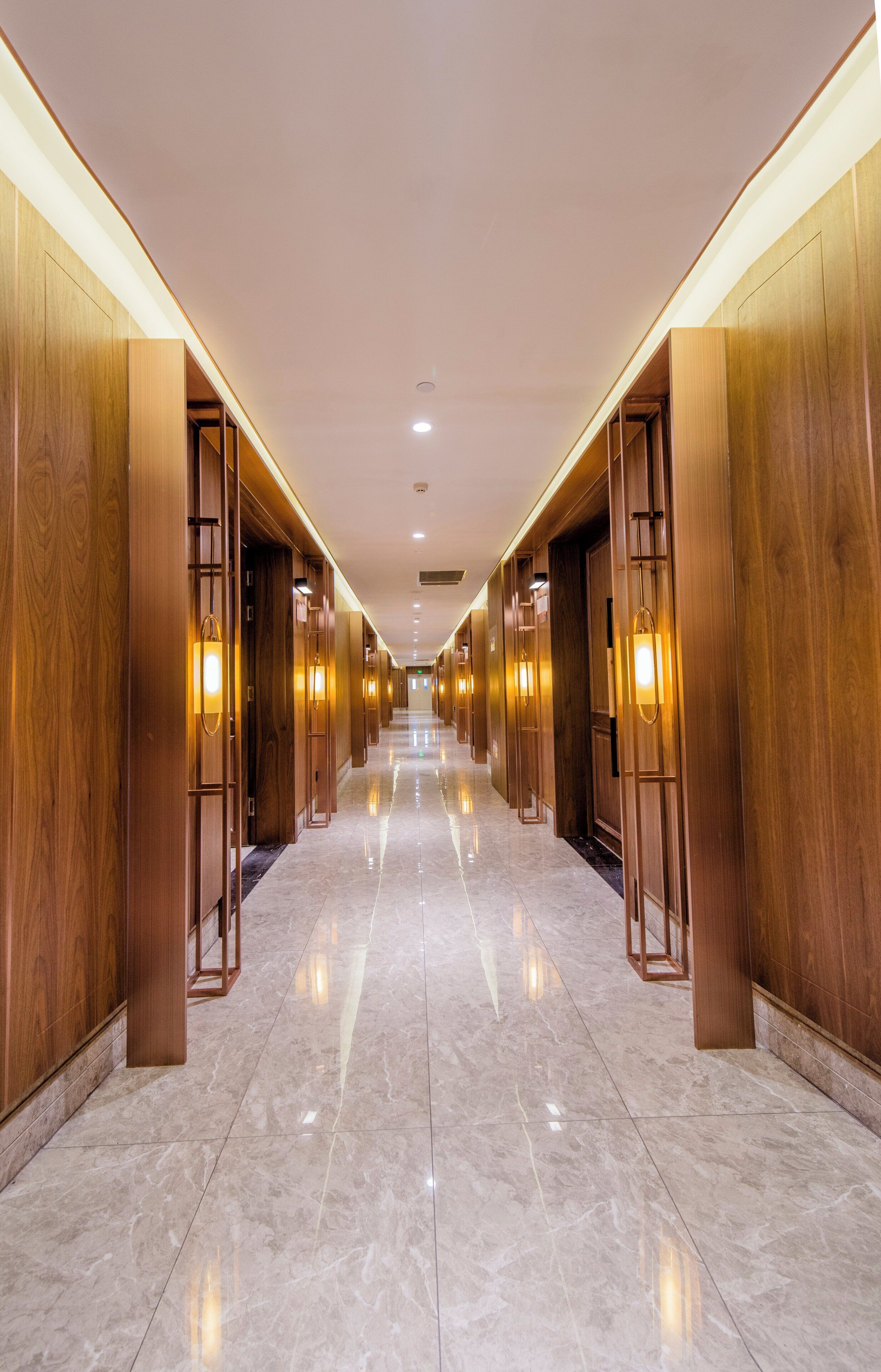 A hotel corridor with wooden paneling and recessed lighting.