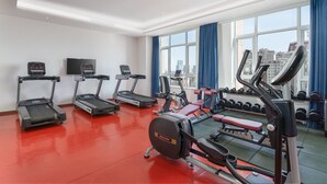 Une salle de sport équipée de tapis de course, d’un appareil elliptique et d’un banc de développé couché.