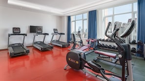 Une salle de sport équipée de tapis de course, d’un appareil elliptique et d’un banc de développé couché.