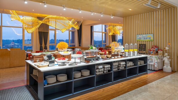 Un buffet proposant une variété de plats et un coin café, installé dans une pièce dotée de grandes fenêtres offrant une vue sur la ville.