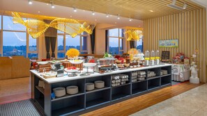 A buffet setup with various food items and a coffee station, located in a room with large windows and a city view. - Holiday Inn Express Yinchuan Downtown by IHG (Yinchuan)