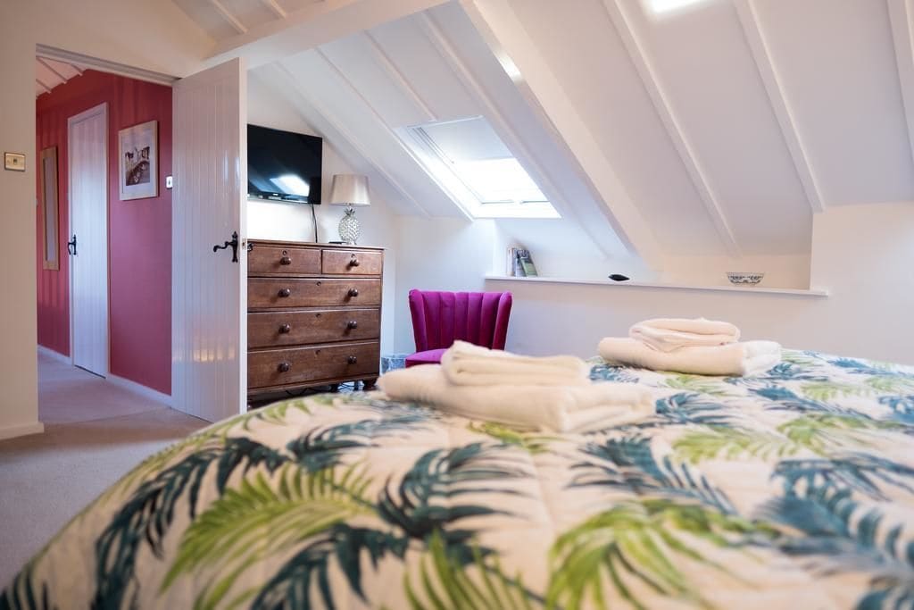 A bedroom with a bed, a dresser, a chair, and a skylight.