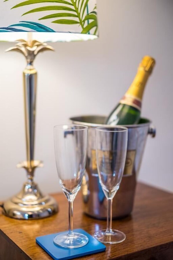Two empty champagne flutes on a wooden table with a blue coaster, a metal champagne bucket, and a green bottle of champagne. - The Horseshoe Inn (Pickering)