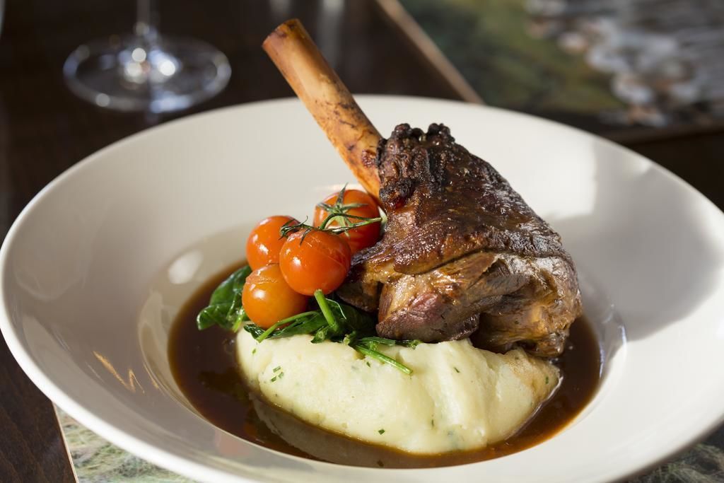 A plate with a steak, cherry tomatoes, and mashed potatoes.