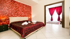 A hotel room with a large bed, a nightstand, a lamp, and a view of a red curtained balcony. - Sosta dei Garibaldini (Campofelice di Roccella)