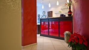 A reception area with a red counter, a potted plant, and a tiled floor. - Sosta dei Garibaldini (Campofelice di Roccella)