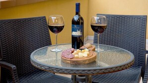 A round glass table with two wine glasses and a bottle of wine, surrounded by wicker chairs. - Sosta dei Garibaldini (Campofelice di Roccella)