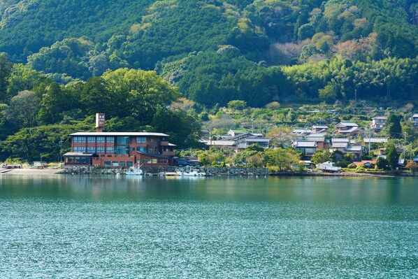 A waterfront property with a large building, a dock, and a hillside with dense greenery. - Owase Seaside View (Owase)
