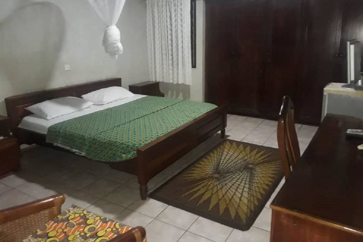 A bedroom with a bed, a nightstand, a wooden table, and a chair.
