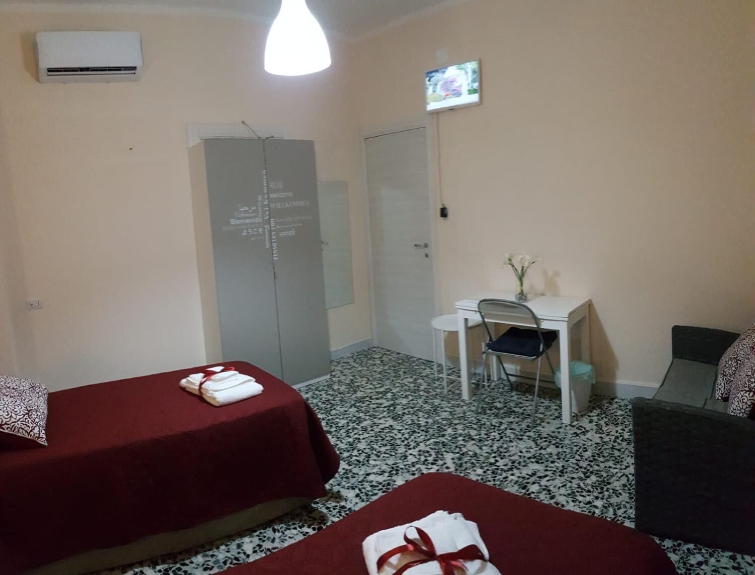 Habitación de hotel con dos camas, un escritorio, una silla, un televisor y un armario.