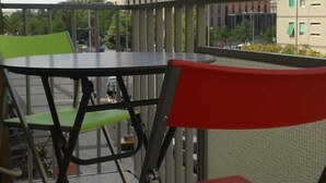 A balcony with a table and chairs, overlooking a cityscape with buildings. - Edelweiss B&B (Salerno)