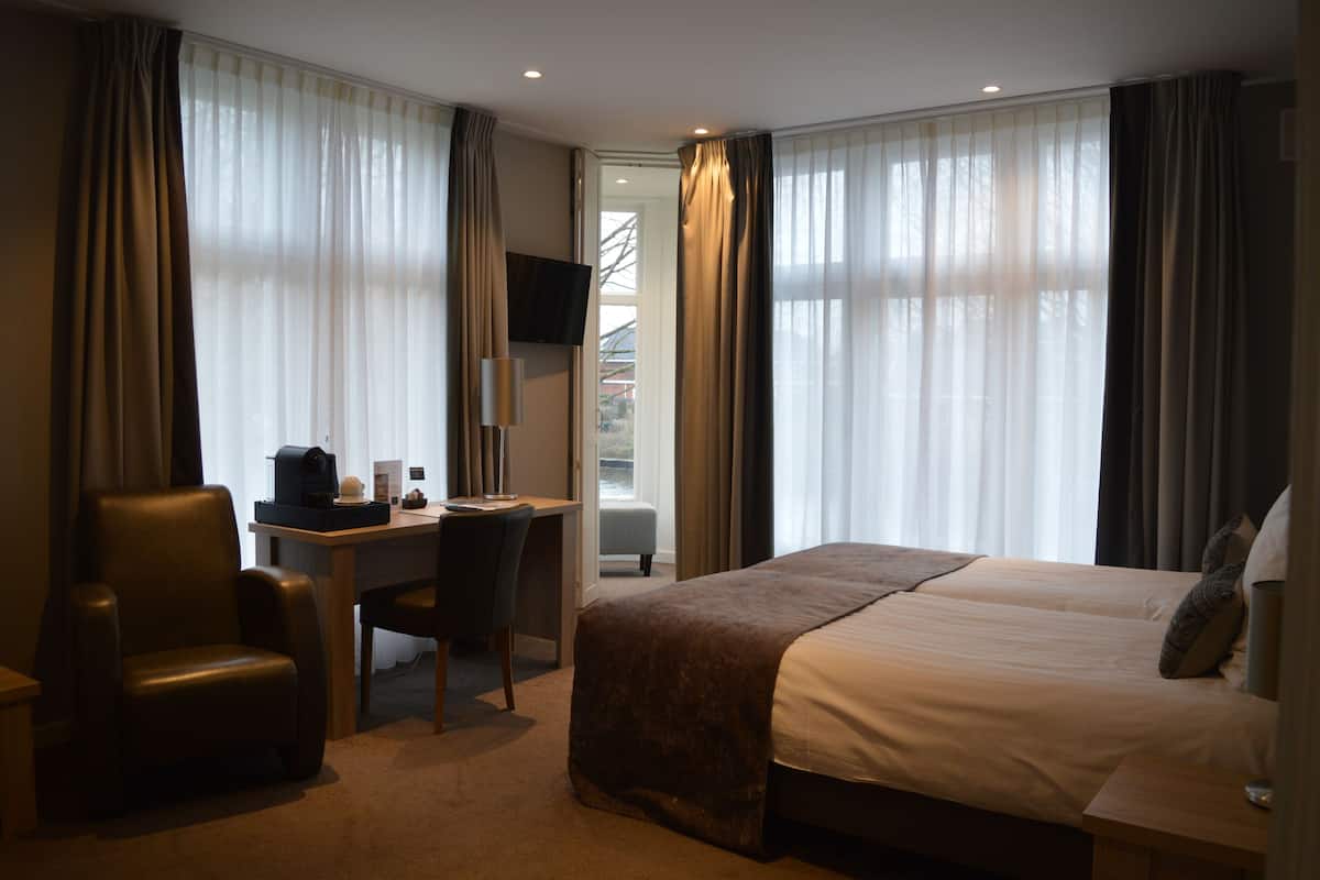 Een hotelkamer met een bed, bureau, stoel en televisie.