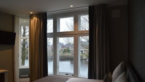 Een hotelkamer met een bed, een televisie en een groot raam met gordijnen.