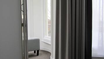 A room with a window, a grey bench, and a white door.