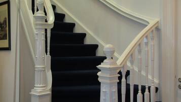 Una escalera con balaustres blancos y una alfombra negra.