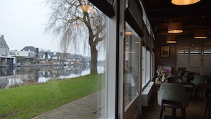 Een restaurant met uitzicht op een gracht en huizen.