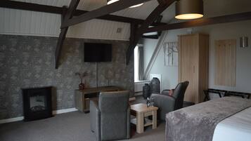 A modern bedroom with a sloped ceiling, a fireplace, a desk, and a bed.