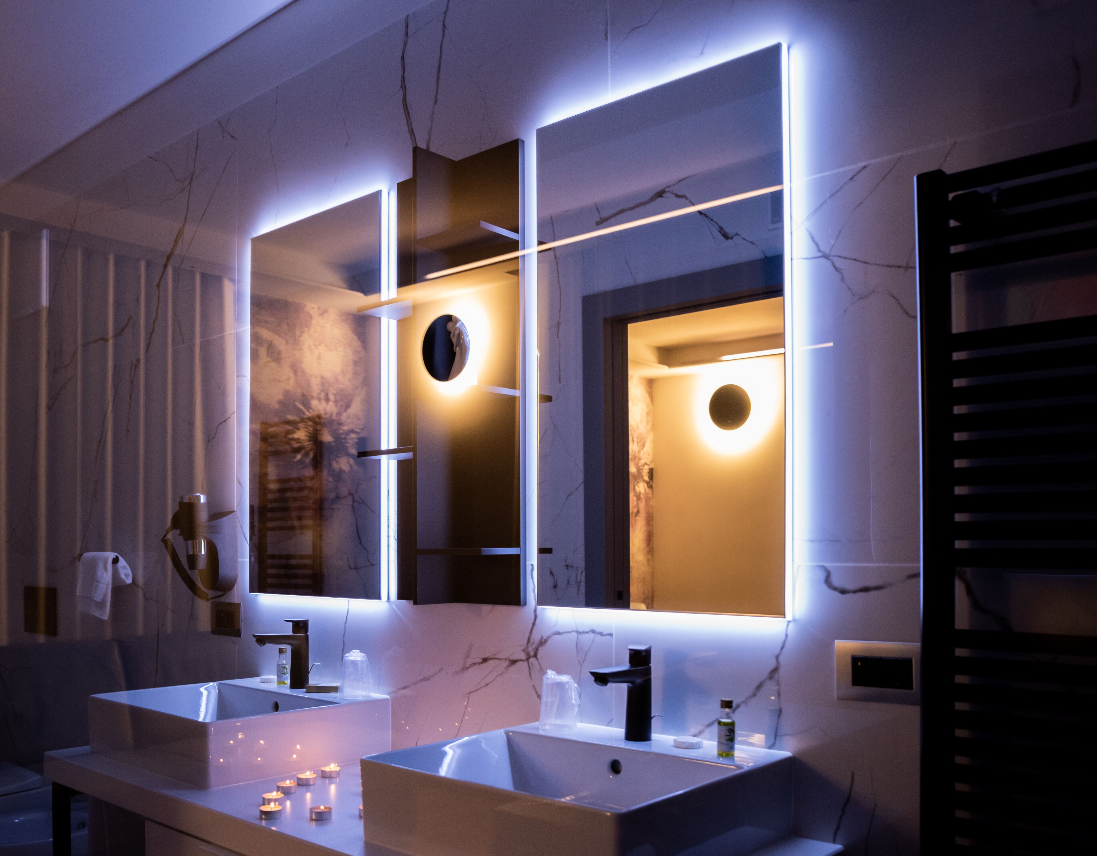 Un baño moderno con dos lavamanos, un espejo e iluminación debajo del gabinete.