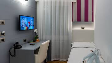 Una moderna camera d'albergo con una scrivania, una sedia e un letto con un peluche.