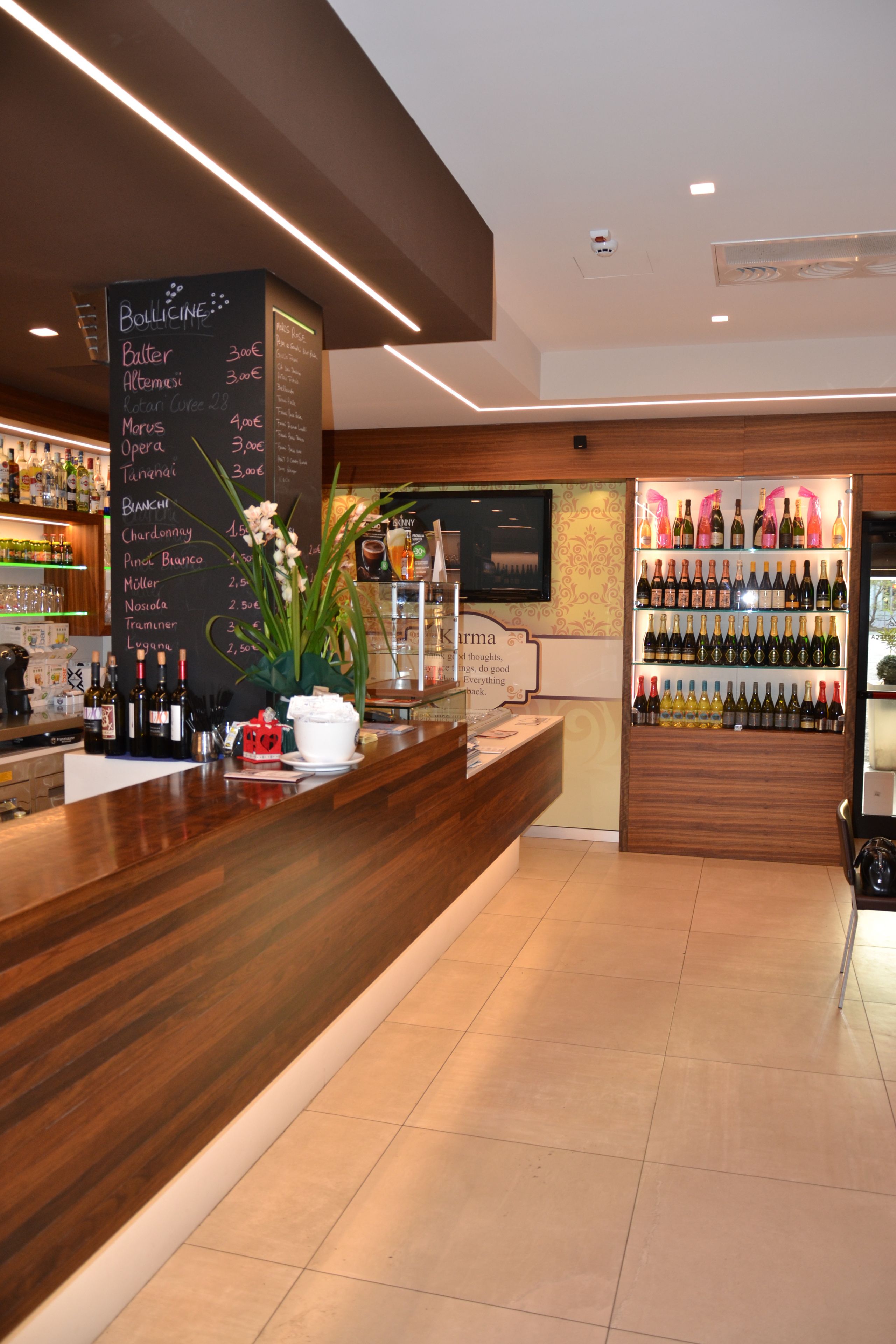 Zona de bar con mostrador de madera, menú en una pizarra y exhibición de vinos.