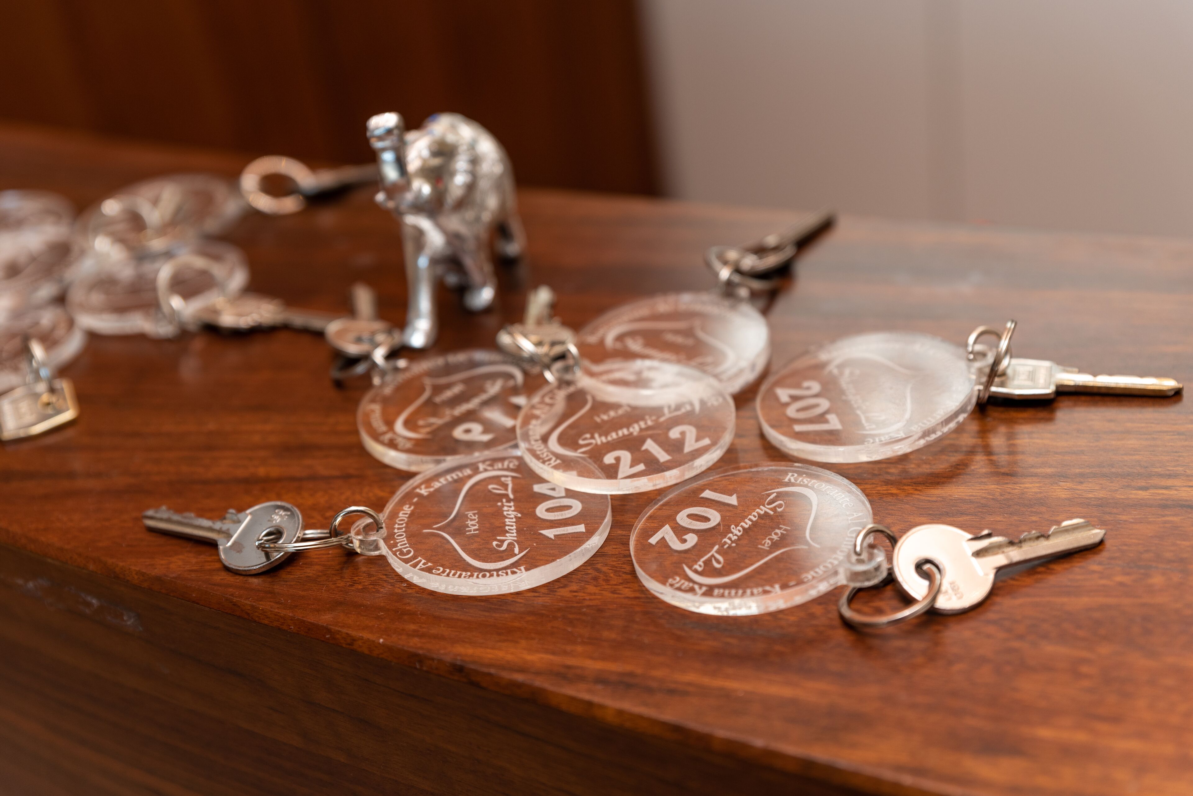A wooden surface with keys and keychains, some with engraved numbers and text.